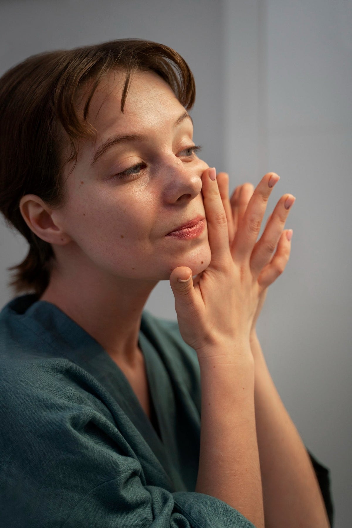 Medium shot woman massaging face at home
